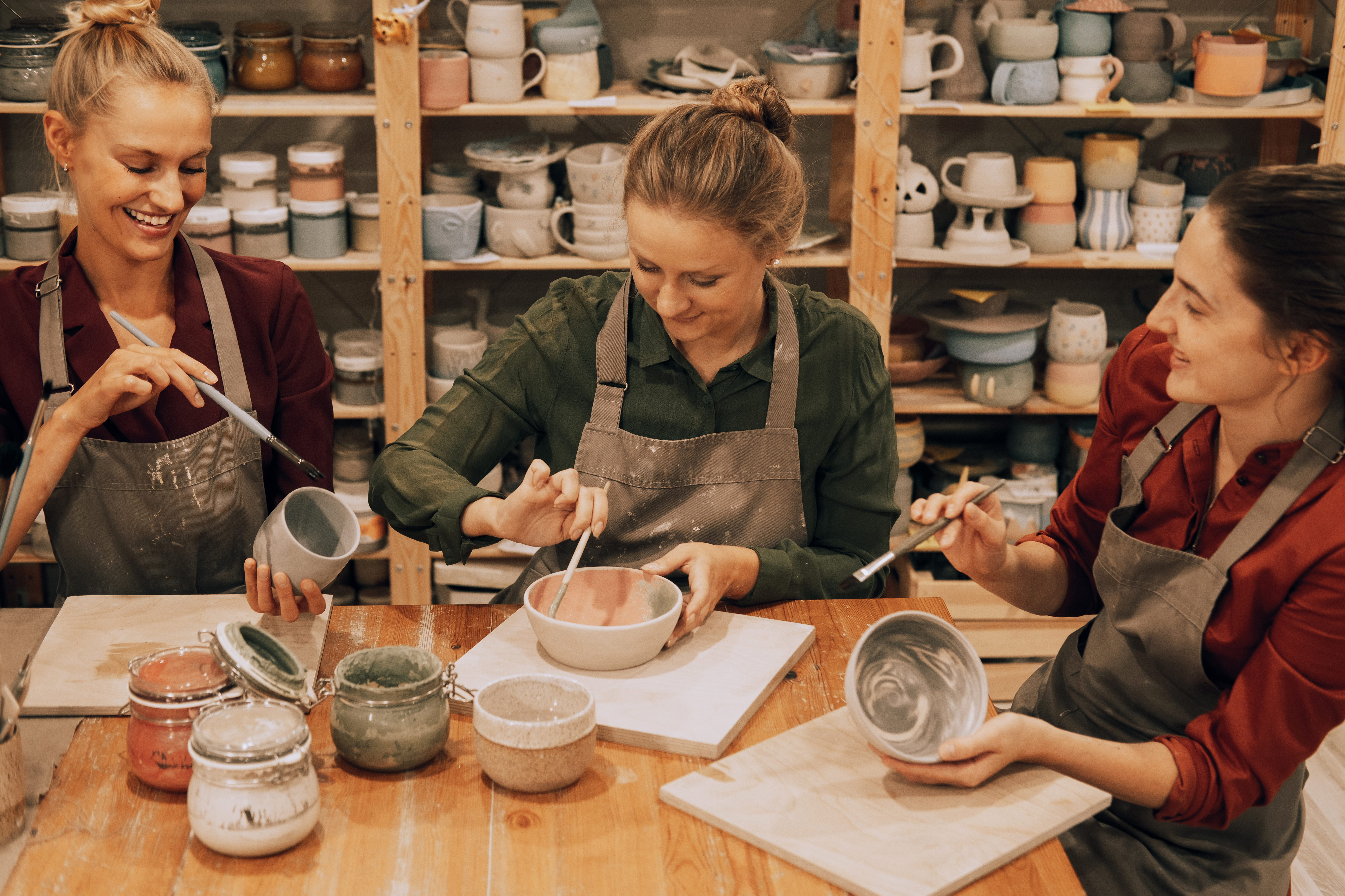 group of women painting pottery in a ceramics studio